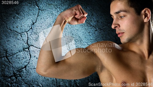 Image of close up of young man flexing and showing biceps