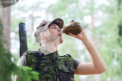 Image of young soldier with gun and flask in forest