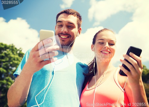 Image of two smiling people with smartphones outdoors