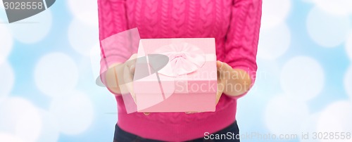 Image of close up of woman in pink sweater holding gift box