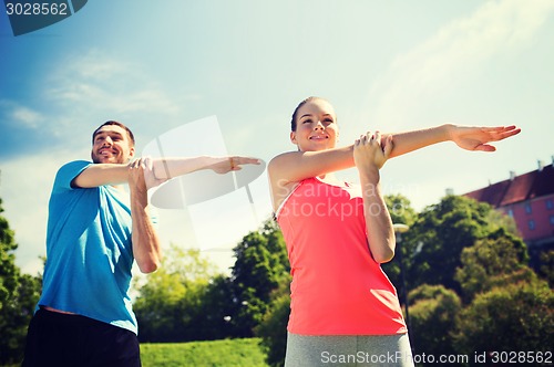 Image of smiling couple stretching outdoors