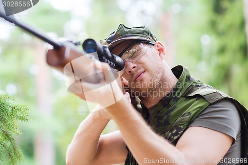 Image of young soldier or hunter with gun in forest