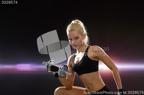 Image of young sporty woman with heavy steel dumbbell