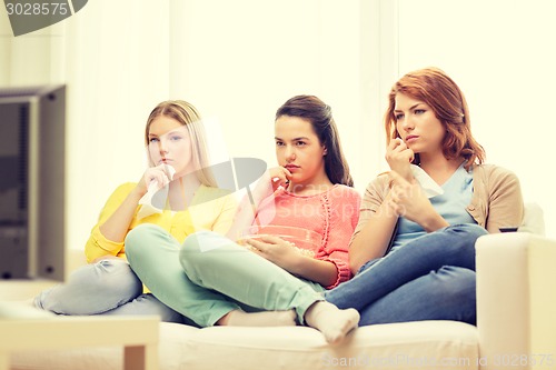 Image of three sad teenage girl watching tv at home