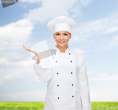 Image of smiling female chef holding something on hand