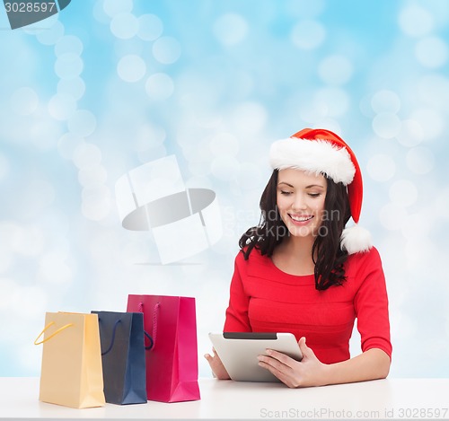 Image of smiling woman with shopping bags and tablet pc