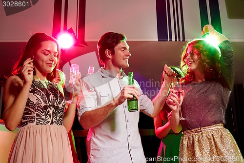 Image of smiling friends with wine glasses and beer in club