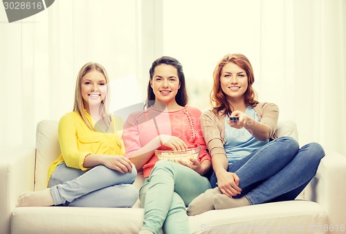 Image of three smiling teenage girl watching tv at home