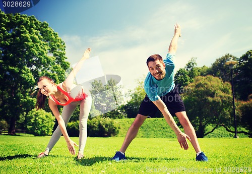 Image of smiling couple stretching outdoors