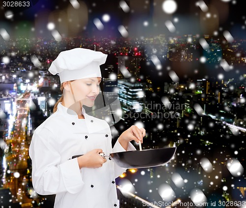 Image of smiling female chef with pan and spoon