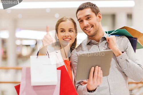 Image of couple with tablet pc and shopping bags in mall