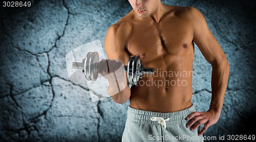 Image of close up of young man with dumbbell flexing biceps