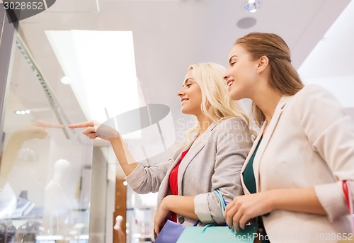 Image of happy young women with shopping bags in mall