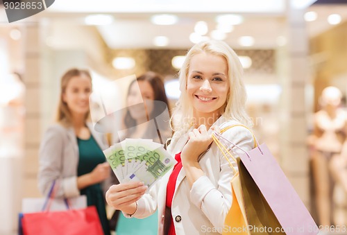 Image of young women with shopping bags and money in mall