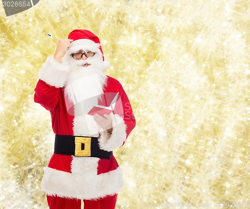 Image of man in costume of santa claus with notepad