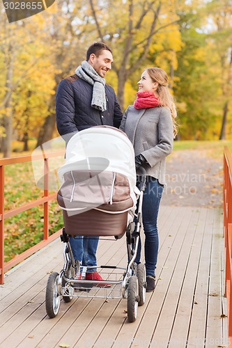 Image of smiling couple with baby pram in autumn park