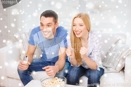 Image of smiling couple watching tv at home