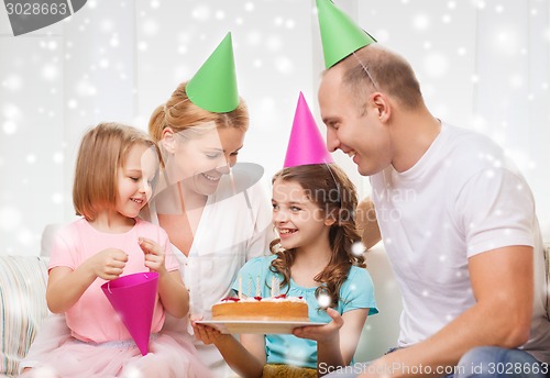 Image of happy family with two kids in party hats at home