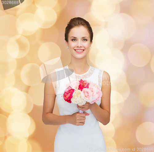 Image of smiling woman in white dress with bouquet of roses