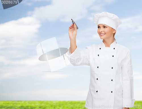 Image of smiling female chef writing something on air
