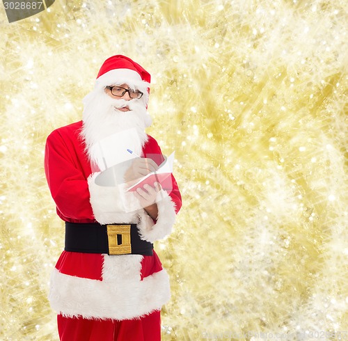 Image of man in costume of santa claus with notepad