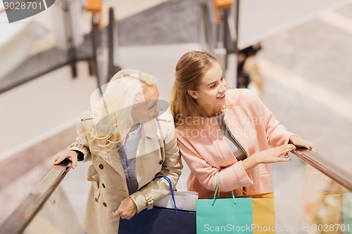 Image of happy young women with shopping bags in mall