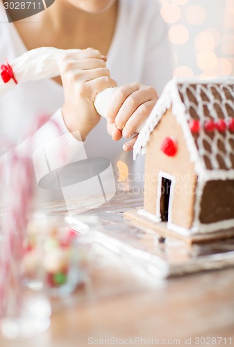 Image of close up of woman making gingerbread house at home