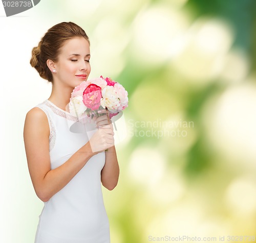 Image of smiling woman in white dress with bouquet of roses