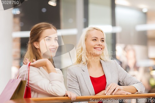 Image of happy young women with shopping bags in mall