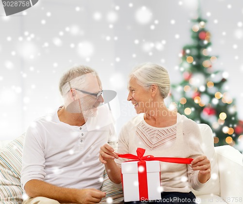 Image of happy senior couple with gift box at home