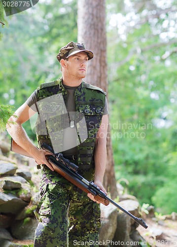 Image of young soldier or hunter with gun in forest