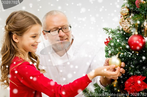 Image of smiling family decorating christmas tree at home