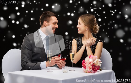 Image of smiling couple with red gift box at restaurant