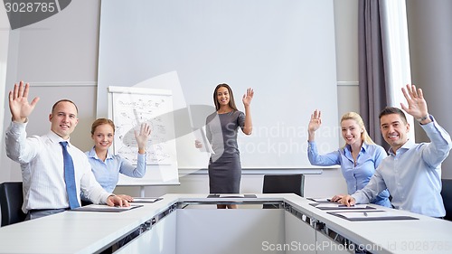 Image of group of businesspeople waving hands in office