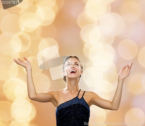 Image of smiling woman raising hands and looking up