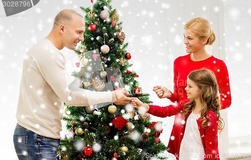 Image of smiling family decorating christmas tree at home