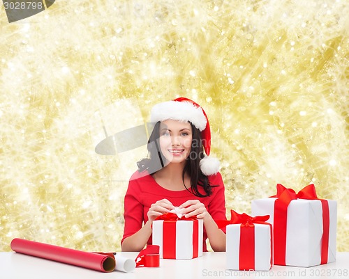 Image of smiling woman in santa helper hats packing gifts