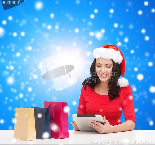 Image of smiling woman with shopping bags and tablet pc