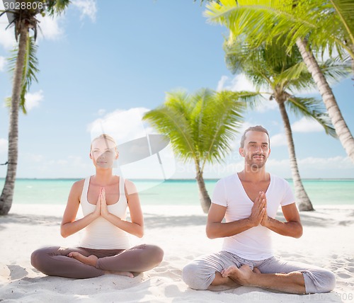 Image of smiling couple meditating on tropical beach