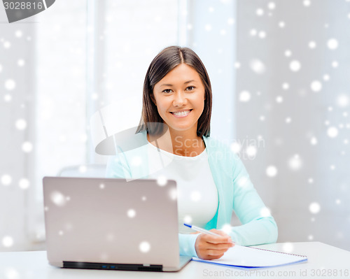 Image of smiling young woman with laptop and notebook