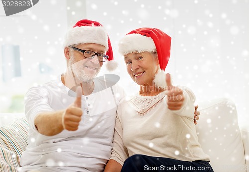 Image of happy senior couple in santa helper hats at home