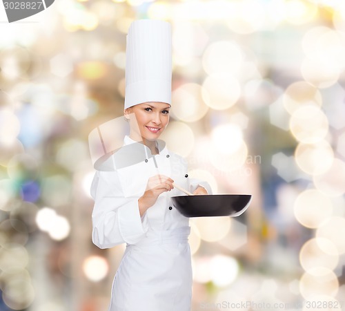 Image of smiling female chef with pan and spoon