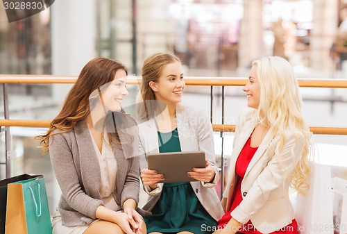 Image of happy young women with tablet pc and shopping bags