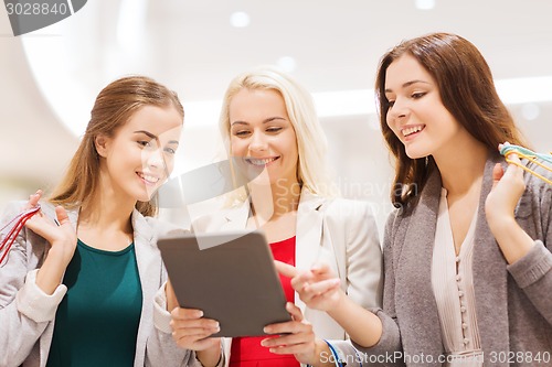 Image of happy young women with tablet pc and shopping bags