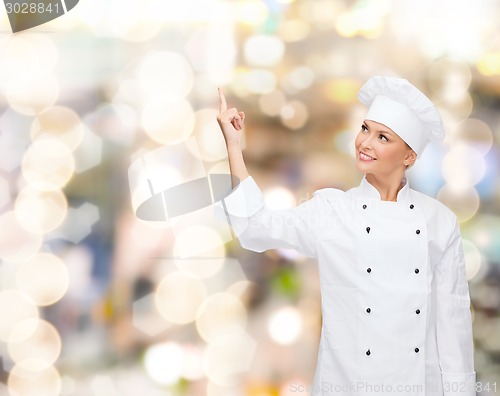Image of smiling female chef pointing finger to something