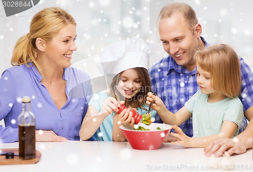 Image of happy family with two kids making salad at home