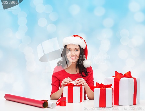 Image of smiling woman in santa helper hats packing gifts