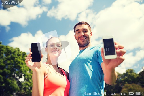 Image of two smiling people with smartphones outdoors