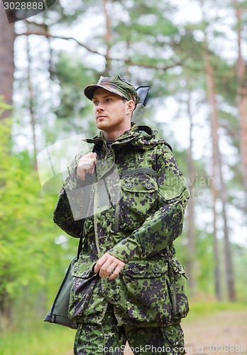 Image of young soldier or hunter with gun in forest