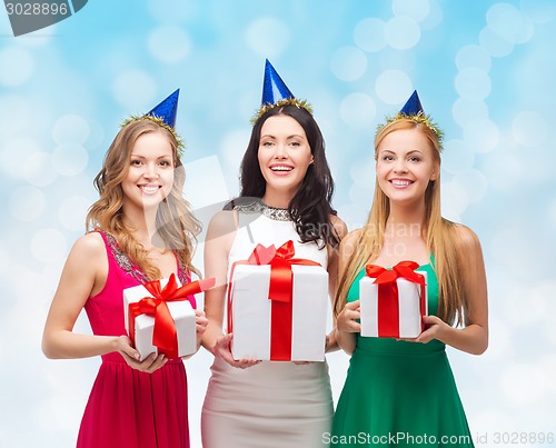 Image of smiling women in party caps with gift boxes